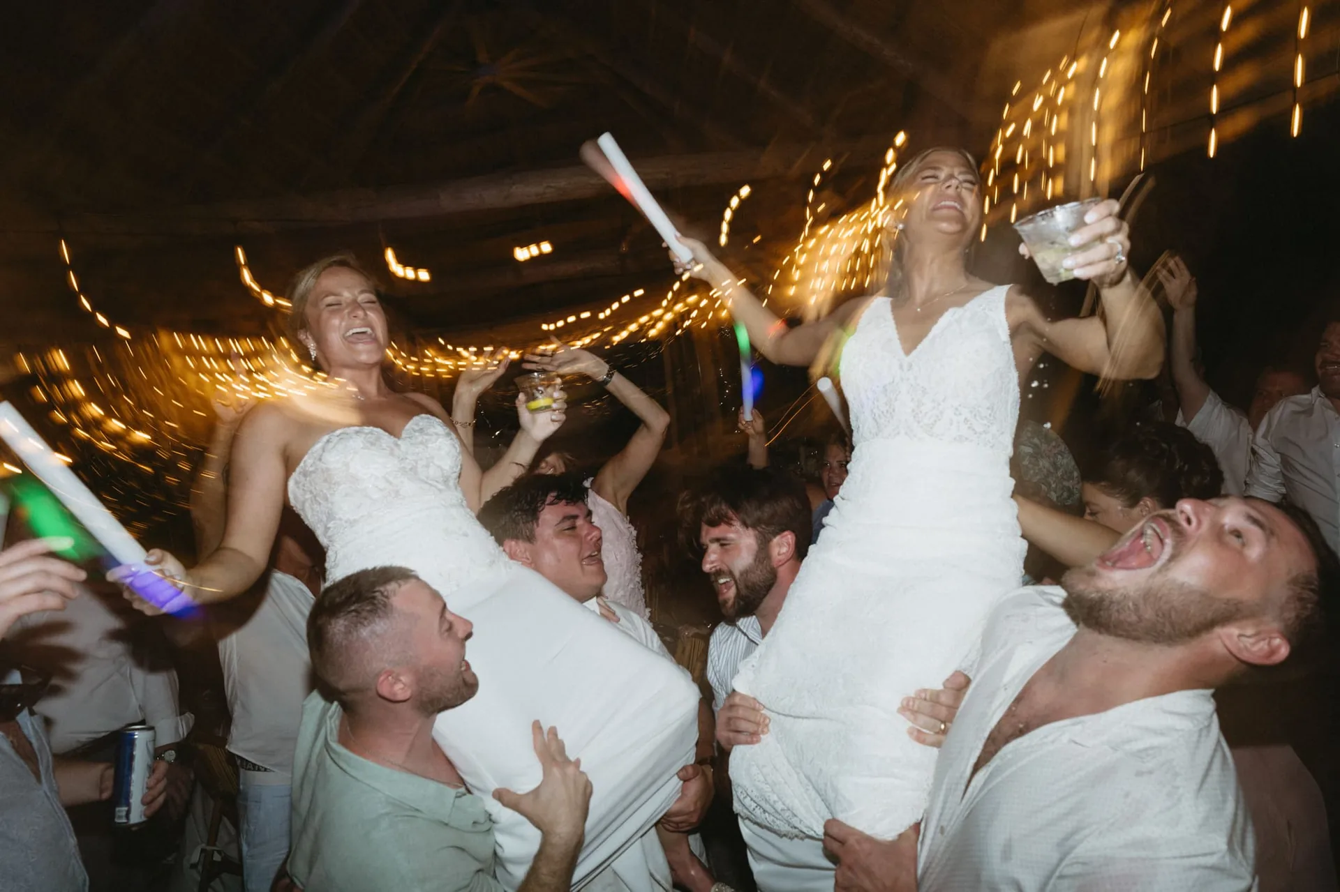 Brides celebrating with glow sticks on a packed South Florida wedding dance floor